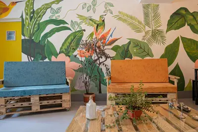 two chairs and a table with flowers on a wall at Laureles Garden Hostel in Medellín