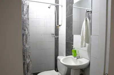 a white bathroom with a toilet and a sink at Laureles Garden Hostel in Medellín