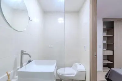 a white bathroom with a toilet and a sink at Mirador del Laureles, AC, Piscina, Parqueadero 701 in Medellín