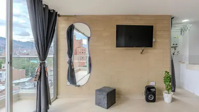 a room with a tv on a brick wall with a mirror at Mirador del Laureles, AC, Piscina, Parqueadero 701 in Medellín