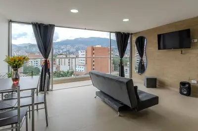 a living room with a couch and a table and a television at Balcón en Laureles, AC, Piscina, Estacionamiento 601 in Medellín