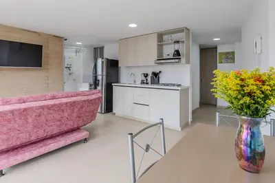 a living room with a pink couch and a vase of flowers at Lindo apartamento en Laureles con piscina 501 in Medellín