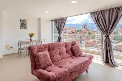a living room with a red couch and a large window at Lindo apartamento en Laureles con piscina 501 in Medellín