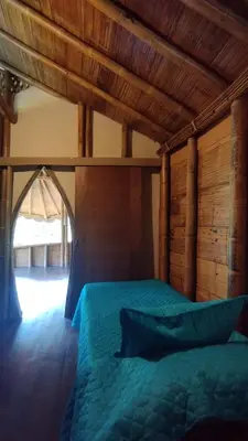 a bedroom with a green bed with a wooden ceiling at Mandi Wasi - Alojamiento Compartido in San Rafael