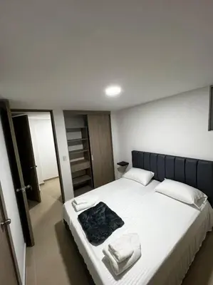 a bedroom with a large white bed with towels on it at Espacioso apartamento con piscina en Laureles 201 in Medellín