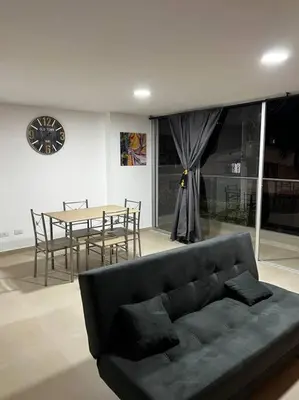 a living room with a couch and a table and a clock at Espacioso apartamento con piscina en Laureles 201 in Medellín