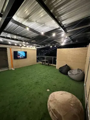 a large room with a green floor and a tv at Espacioso apartamento con piscina en Laureles 201 in Medellín