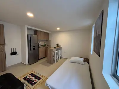a small kitchen with a bed and a refrigerator at Apartaestudio moderno cerca al cable in Manizales