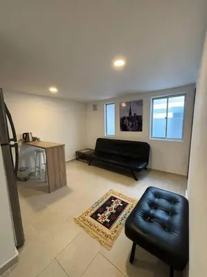 a living room with a black leather couch and a table at Apartaestudio moderno cerca al cable in Manizales