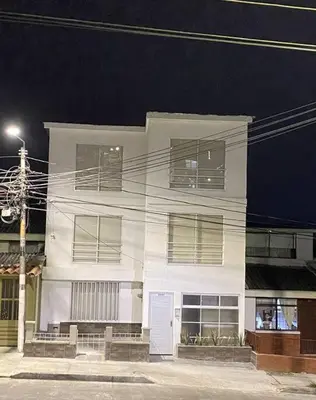 a white building with windows on a street at night at Apartaestudio moderno cerca al cable in Manizales