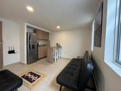a kitchen with a couch and a refrigerator at Apartaestudio moderno cerca al cable in Manizales