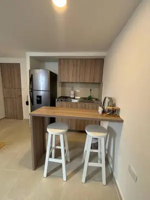 a kitchen with a counter and two stools in it at Apartaestudio moderno cerca al cable in Manizales