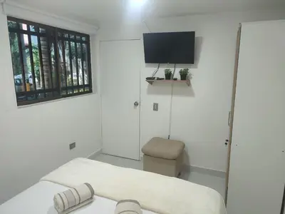 a white room with a couch and a tv at Apartaestudio la 70, estadio in Medellín