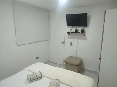 a white room with a bed and a tv at Apartaestudio la 70, estadio in Medellín