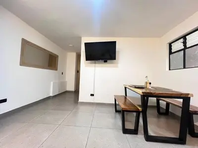 a dining room with a table and a tv on the wall at Elegante apto Laureles Estadio in Medellín