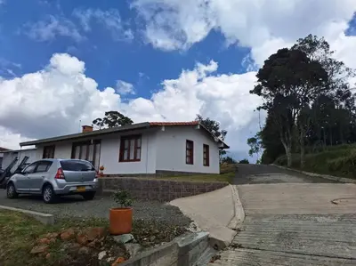 a car parked in front of a white house at Casa San Miguel Santa Elena in Medellín