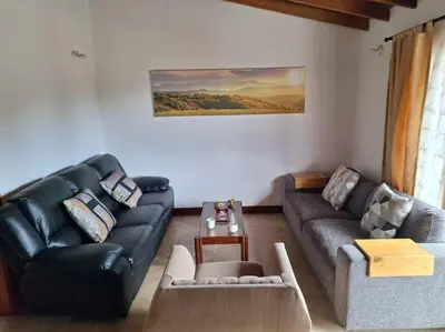 a living room with a black leather couch and a table at Casa San Miguel Santa Elena in Medellín
