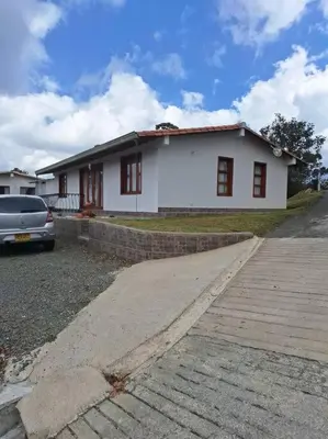 a white house with a car parked in front of it at Casa San Miguel Santa Elena in Medellín