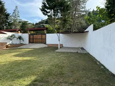 a backyard with a white wall and a fence at Hermosa cabaña en Guarne in Copacabana