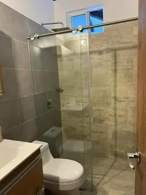 a bathroom with a toilet and a glass shower at Hermosa cabaña en Guarne in Copacabana