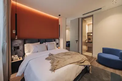 a bedroom with a large bed and a blue chair at Nock - Reserved Residences in Medellín