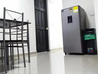 a black refrigerator next to a table and a chair at CASA ESTADIO MEDELLIN Apartamentos Turisticos renovados y modernos cerca al METRO - Barrio Laureles-Estadio in Medellín