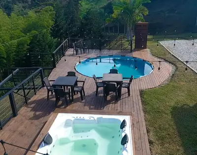 a hot tub on a deck next to a table and chairs at Hermosa finca con vista a la piedra y embalse de Guatapé, con jacuzzi y piscina in Guatapé