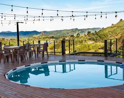 a pool on a deck with a table and chairs at Hermosa finca con vista a la piedra y embalse de Guatapé, con jacuzzi y piscina in Guatapé
