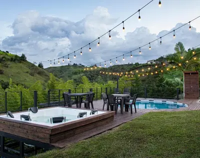 a patio with a hot tub and a table and chairs at Hermosa finca con vista a la piedra y embalse de Guatapé, con jacuzzi y piscina in Guatapé