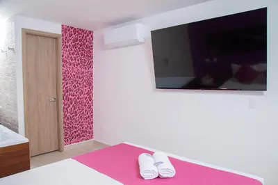 a bedroom with a pink accent wall and a tv at Bajo la luna hotel in Medellín