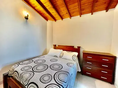 a bedroom with a bed and a wooden dresser at Apto amplio 3 hab para familias y grupos Sabaneta in Sabaneta