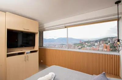 a bedroom with a large window and a television at Apto con la mejor vista del Edificio in Medellín