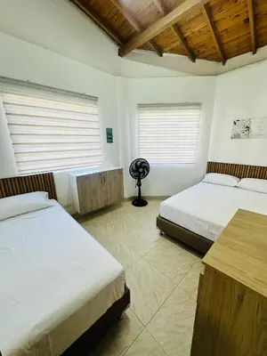 a bedroom with two beds and a desk and two windows at Apartamento Central La Candelaria Medellín in Medellín