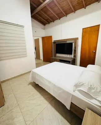 a bedroom with a large white bed and a flat screen tv at Apartamento Central La Candelaria Medellín in Medellín