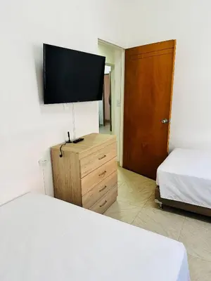 a room with two beds and a flat screen tv at Apartamento Central La Candelaria Medellín in Medellín