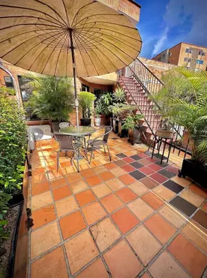a patio with a table and chairs and an umbrella at Colonial Charm House in Medellín