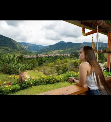 a woman sitting on a bench looking out at the mountains at Cabañas Lucerito Colibrí in Jardin