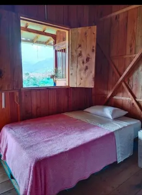 a bedroom with a large bed with a window at Cabañas Lucerito Turpial in Jardin