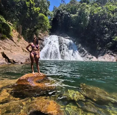 a woman sitting on a rock in the water in front of a waterfall at Cabaña la Antiguita in San Luis