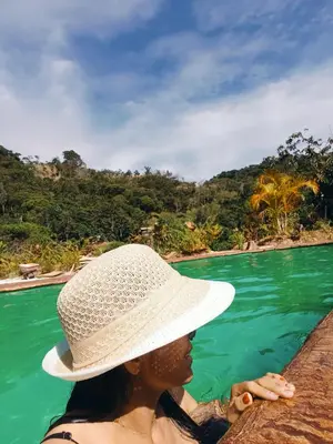 a woman wearing a white hat sitting on a rock in the water at Cabaña la Antiguita in San Luis