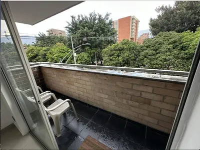 a balcony with a white chair on a brick wall at Acogedor apartamento en Laureles in Medellín