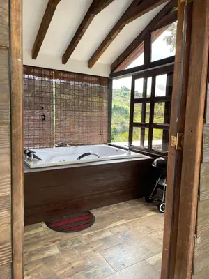 a bath tub in a room with a large window at Cabañas Tahamí con jacuzzi cerca al Aeropuerto in Guarne