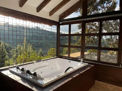 a large bath tub in a room with windows at Cabañas Tahamí con jacuzzi cerca al Aeropuerto in Guarne
