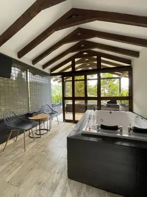 a living room with a tub and a table and chairs at Cabañas Tahamí con jacuzzi cerca al Aeropuerto in Guarne