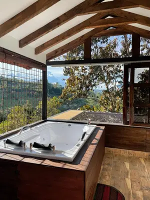 a bath tub in a room with a large window at Cabañas Tahamí con jacuzzi cerca al Aeropuerto in Guarne