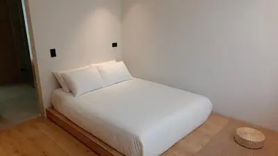 a bed with white sheets and pillows in a room at Casa Tokyo Manila By Xcay Home in Medellín