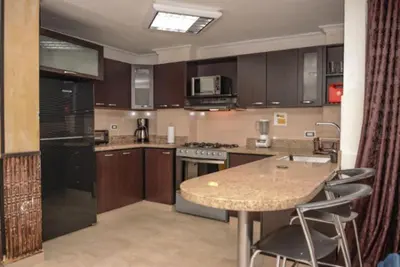 a kitchen with wooden cabinets and a table with chairs at Poblado medellin cll8 101 in Medellín