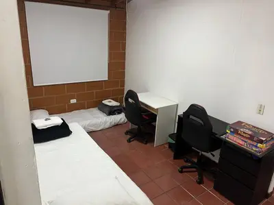 a room with two beds and a desk and chairs at Kyra Sol Cinehome El Carmen Carmen de Viboral Cerca al Centro in Carmen de Viboral