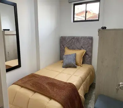 a small bedroom with a bed with a mirror at Loft Céntrico en Medellín Plaza Mayor y Parking 309 in Medellín