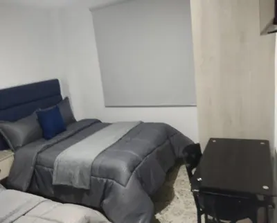 a bedroom with a bed and a desk with a laptop at Céntrico Familiar Vive y disfruta Medellín 107 in Medellín